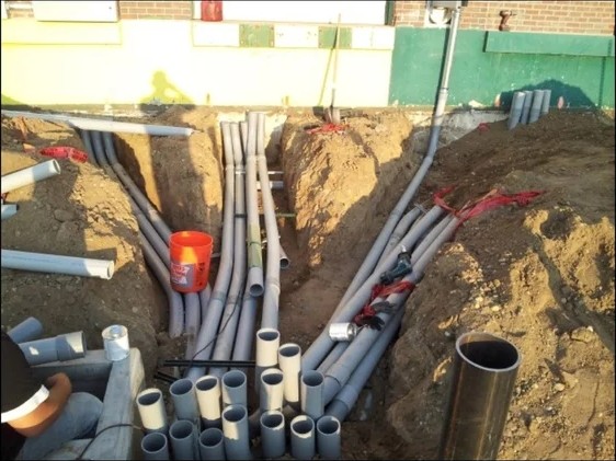 Underground PVC conduit runs staged in an open trench