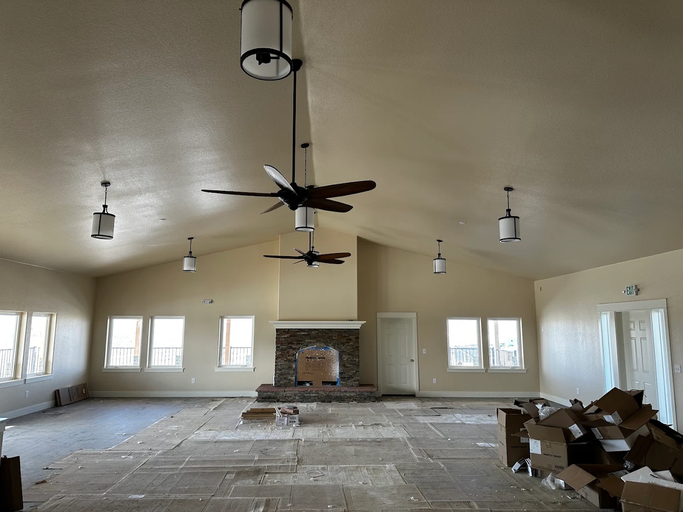 Vaulted great room with pendant lights and ceiling fans installed