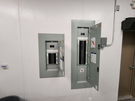 Two interior electrical panels with breakers labeled and door open